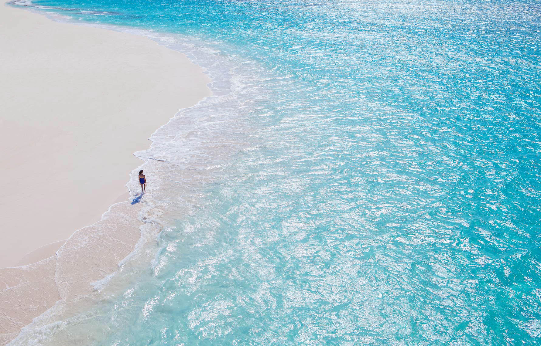 An aerial photo of a woman walking on the beach at Baker's Bay, Great Guana Cay in the Abaco Islands Bahamas for Discovery Land Company.