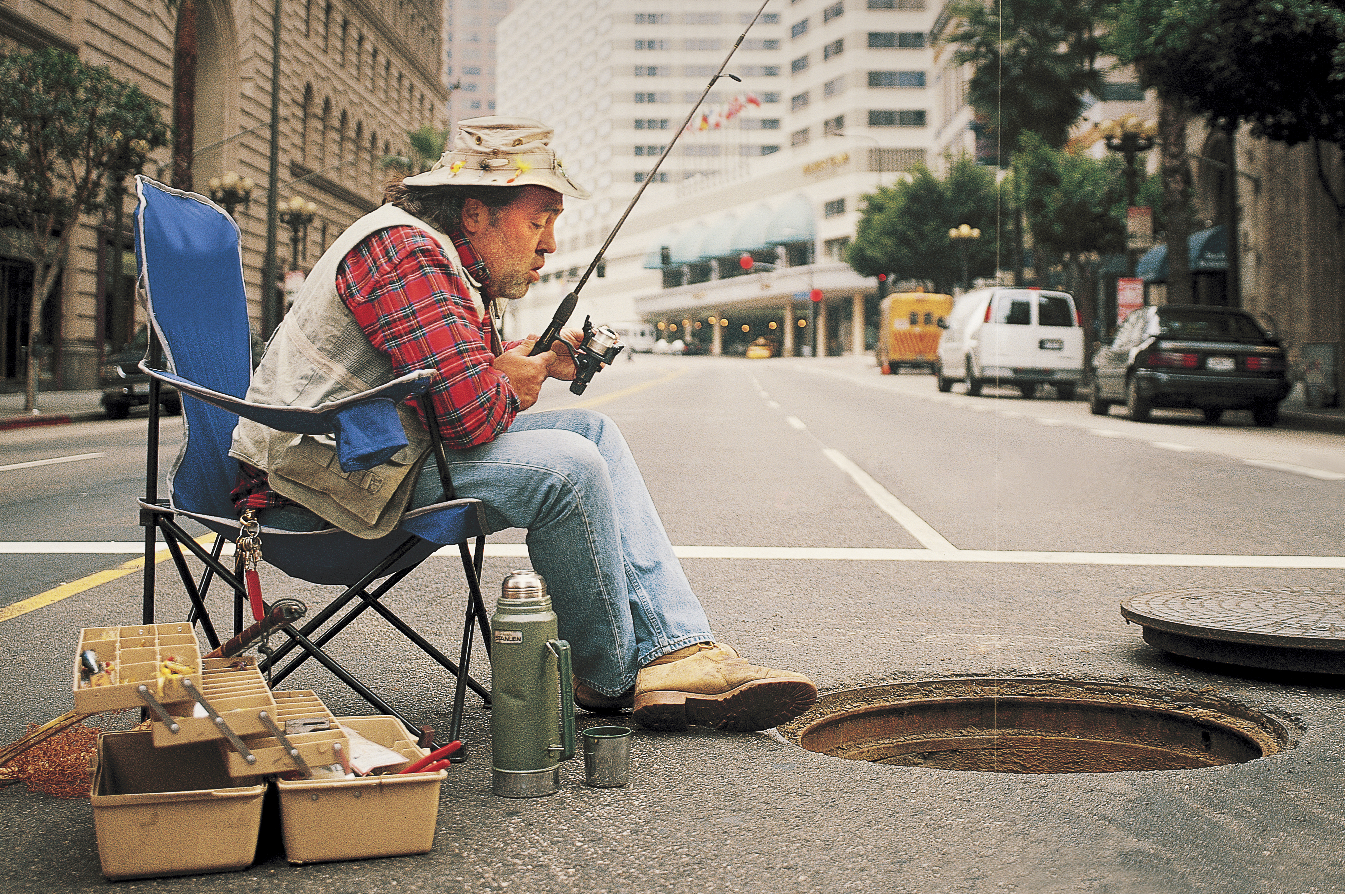 Man Fishing in man hole on city street. Yamaha
