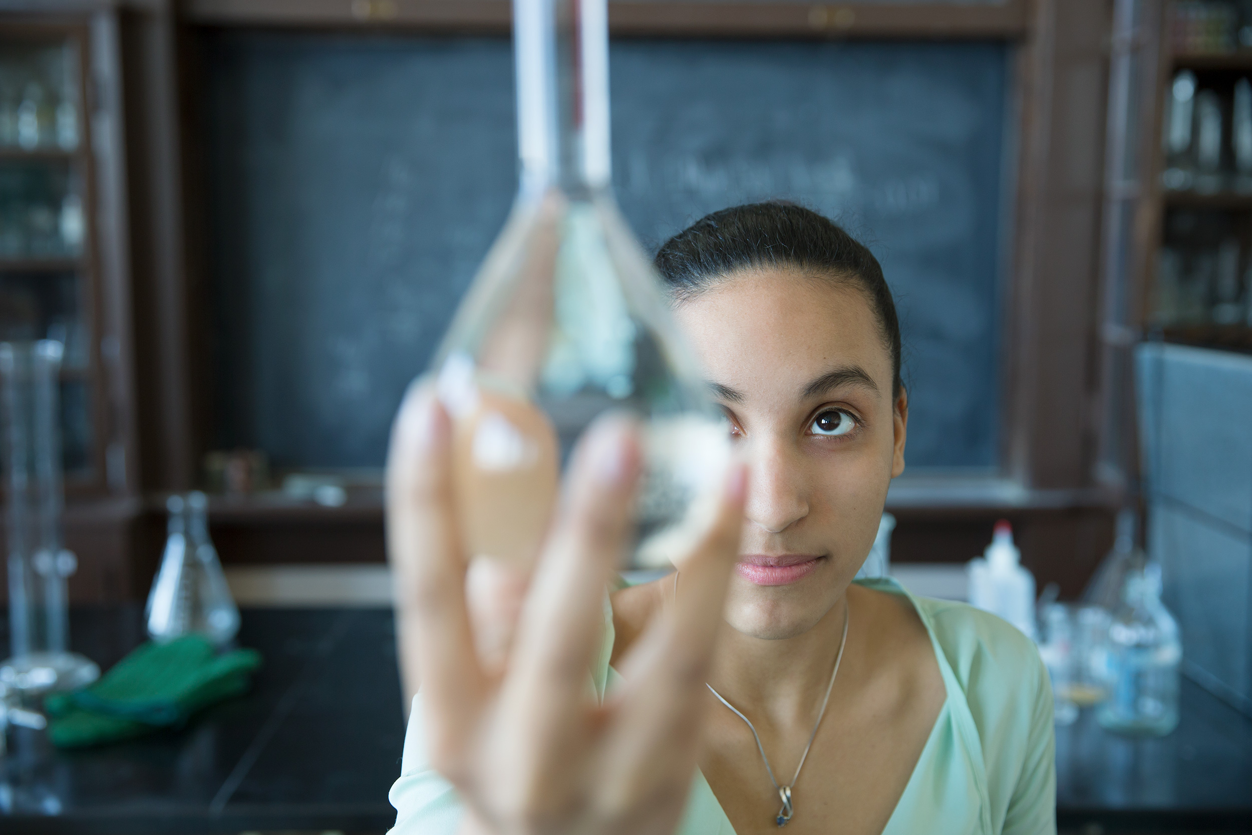 Female student examining flask in science classroom