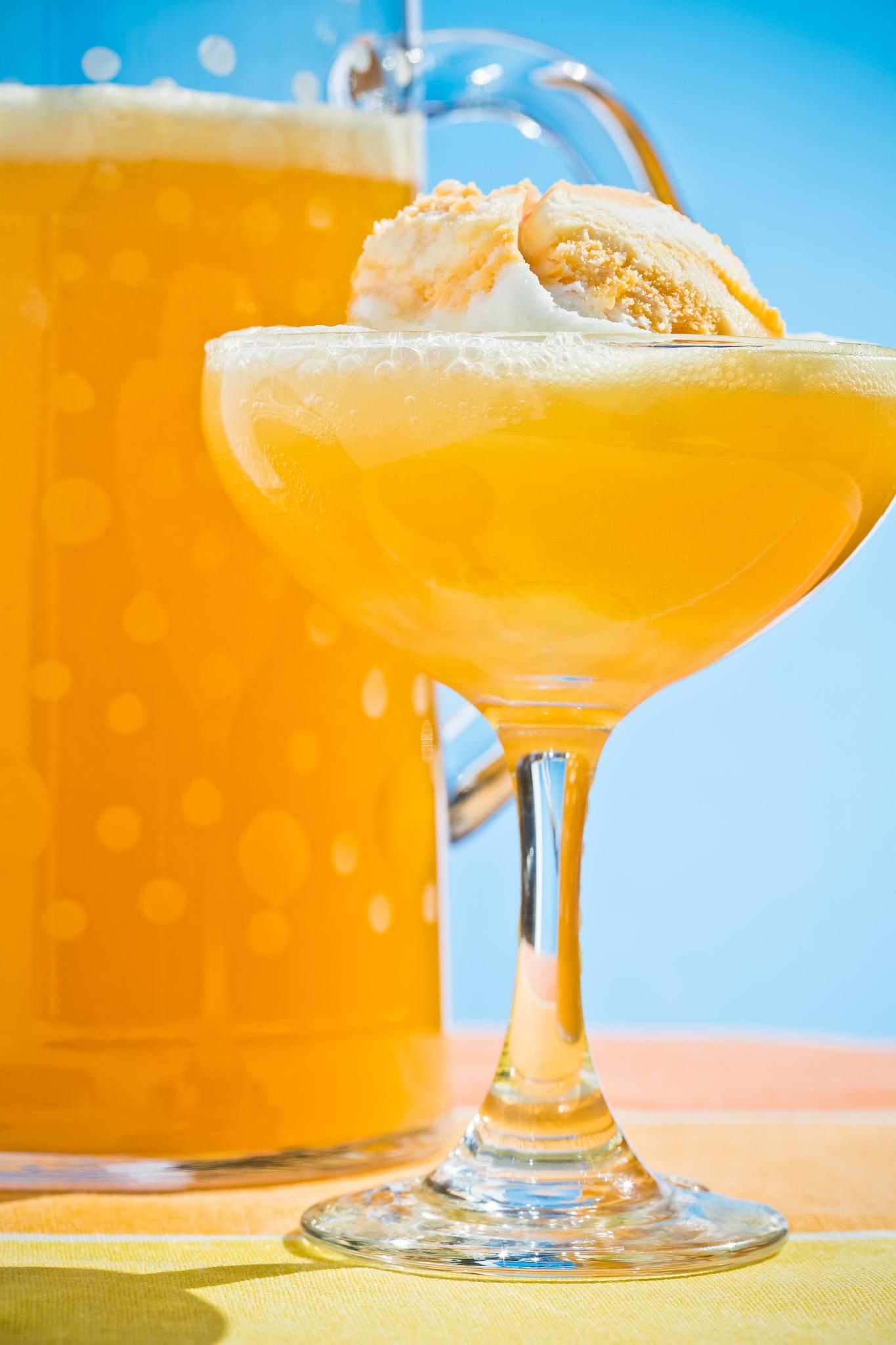 Photograph of a traditional champagne glass filled with punch and a scoop of sherbet with a pitcher of more punch in the background. © 2015 Dana Hursey Photography
