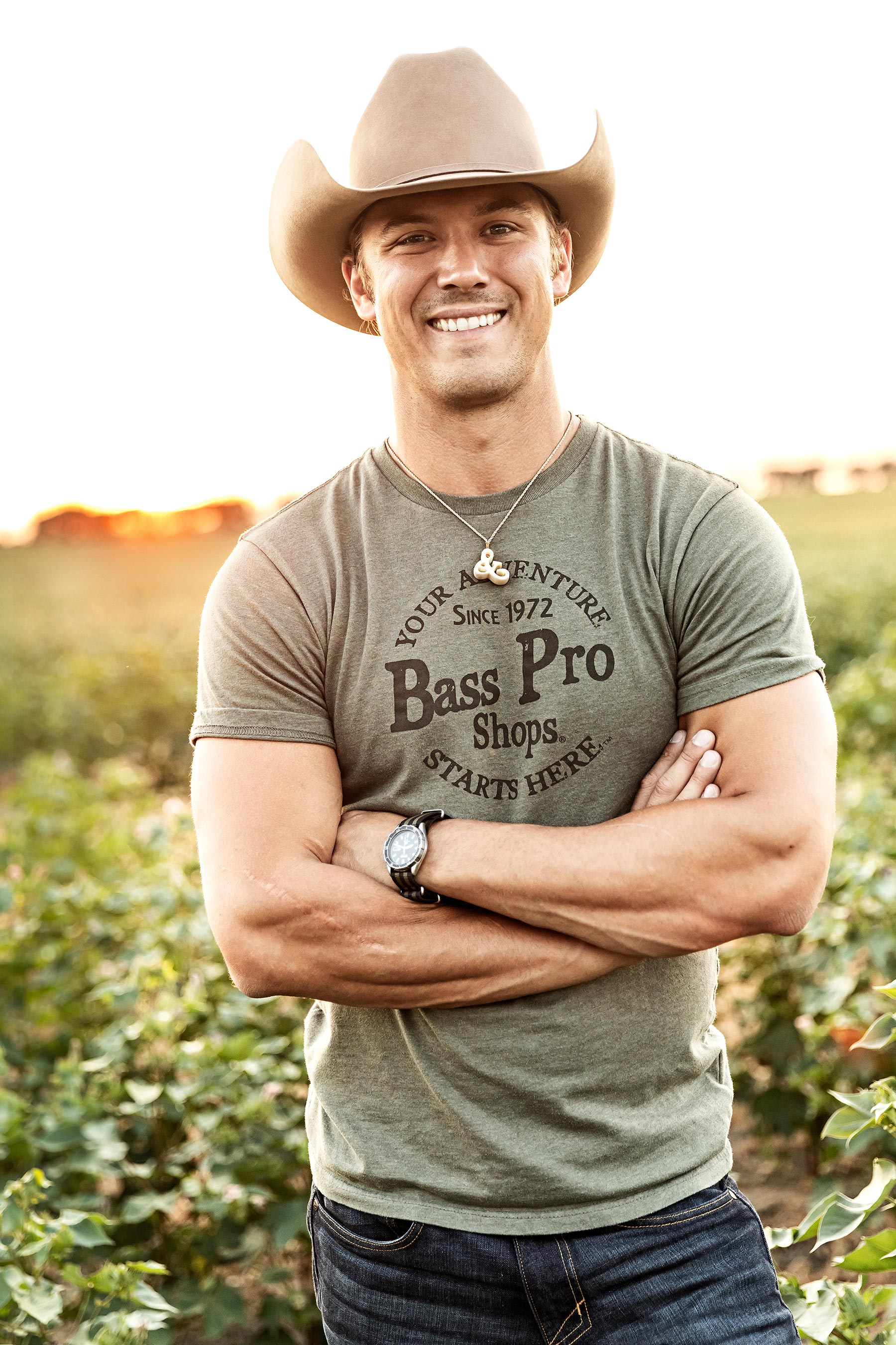 Portrait of a young man with a cowboy hat in a field near sunset 