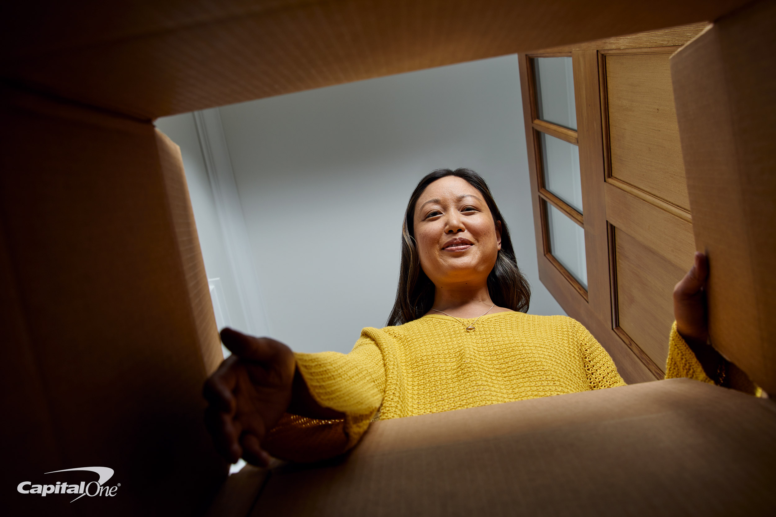 A woman opens a box at her front door.