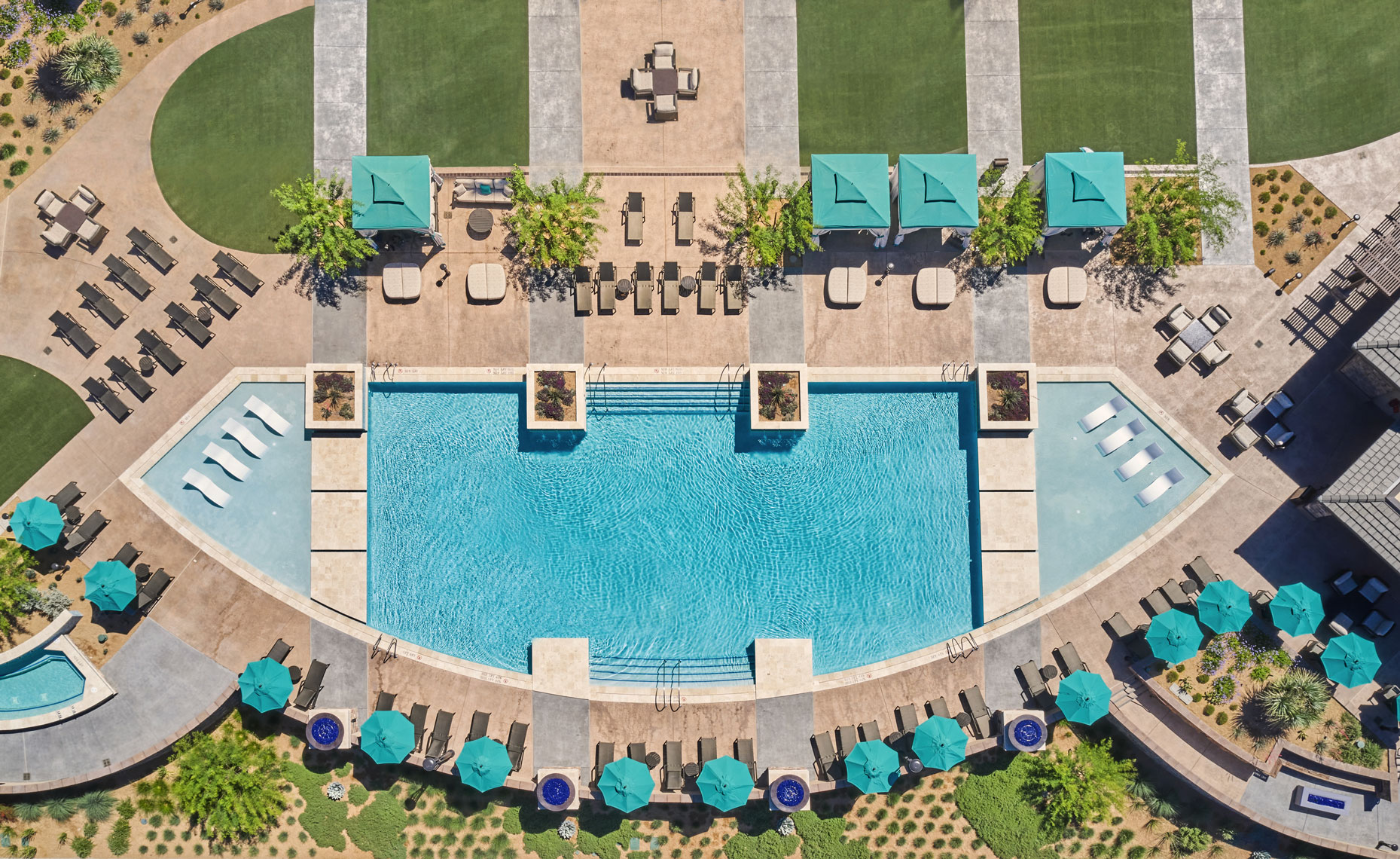 A drone captures a striking overhead shot of a colorful and enticing resort pool. 