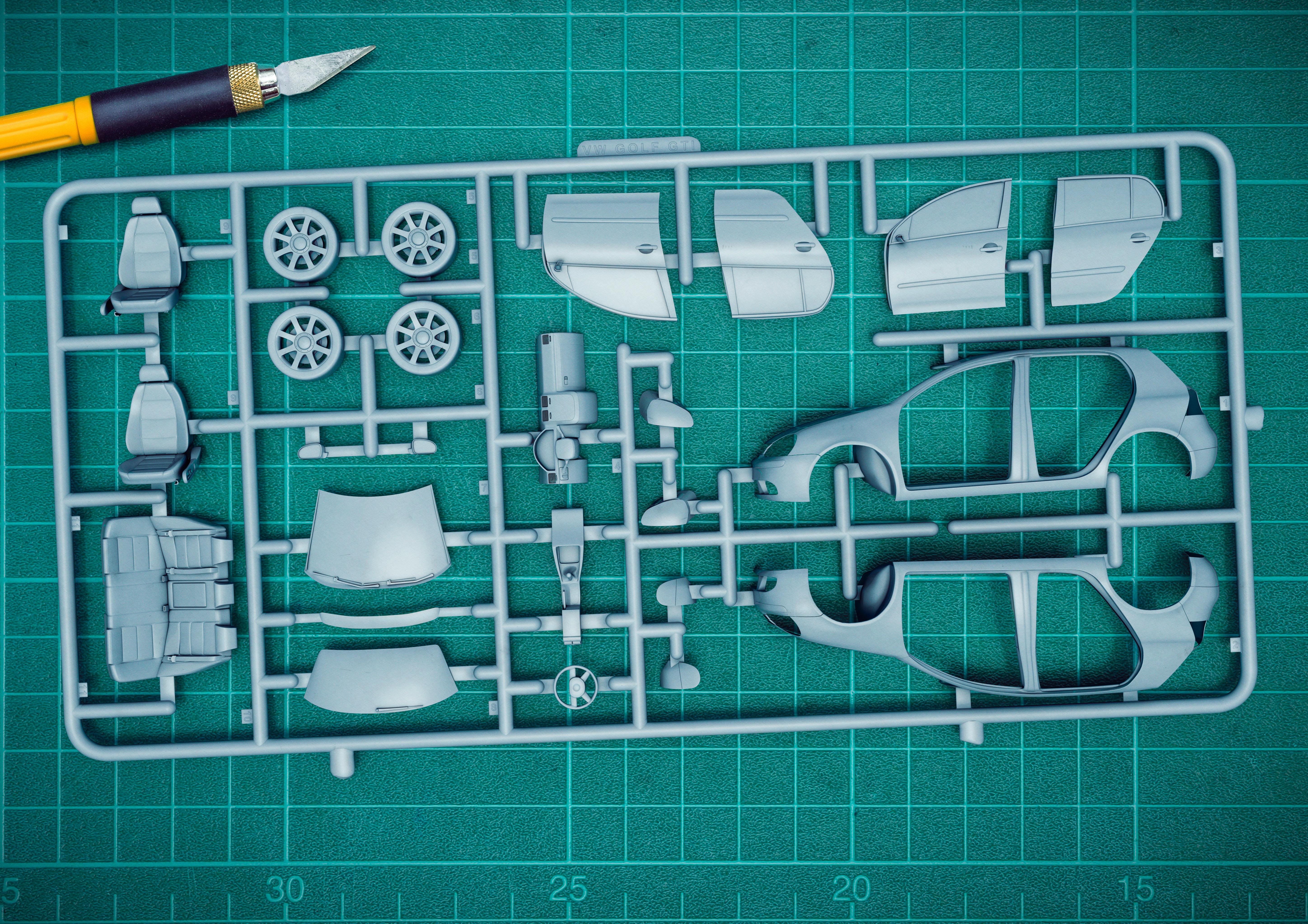 Grey airfix car model layout on top of a green cutting matt with craft knife top left conner. 