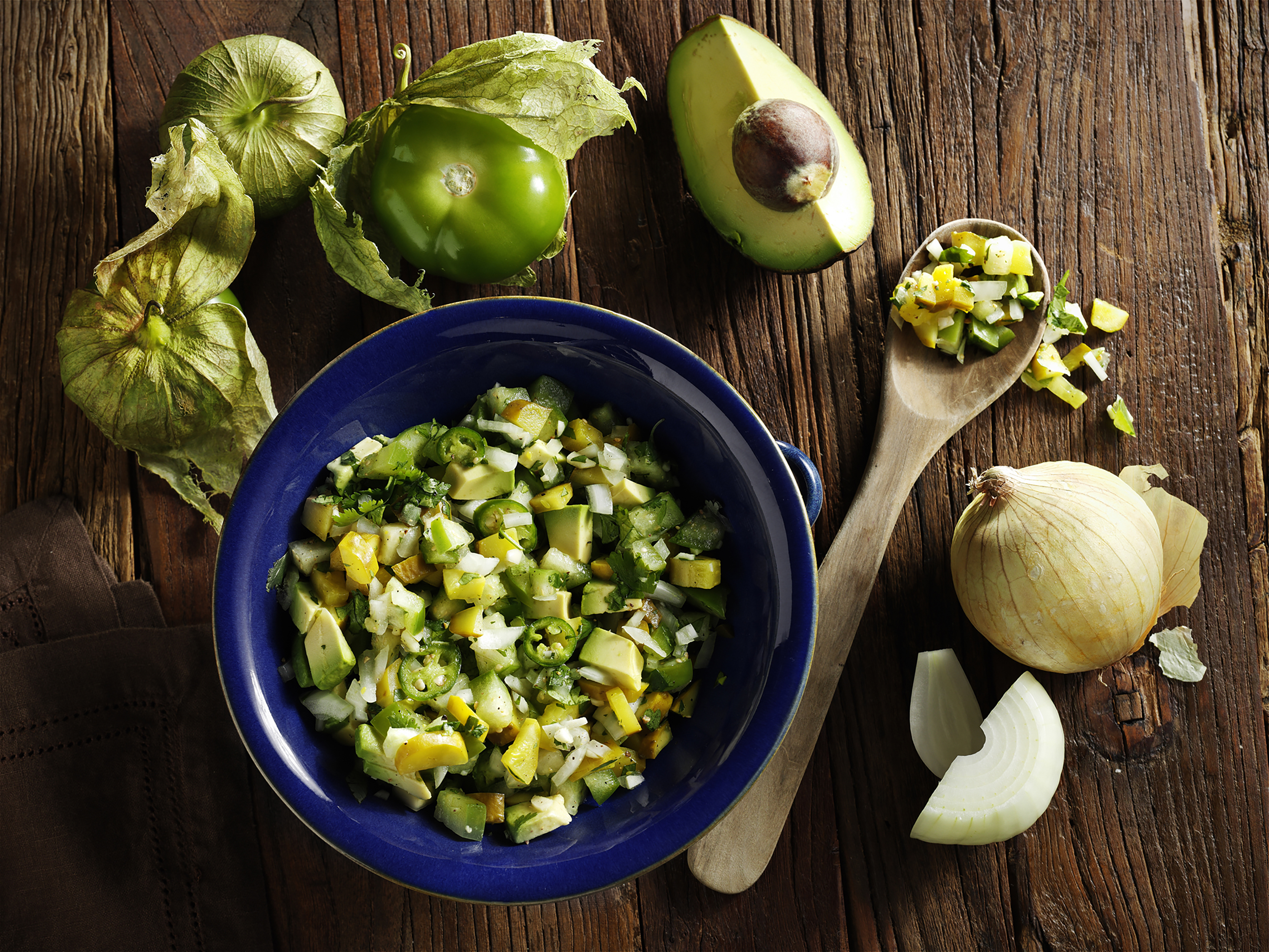 Recipe image shot overhead for food company with tomatillos avocado and onion on rustic surface