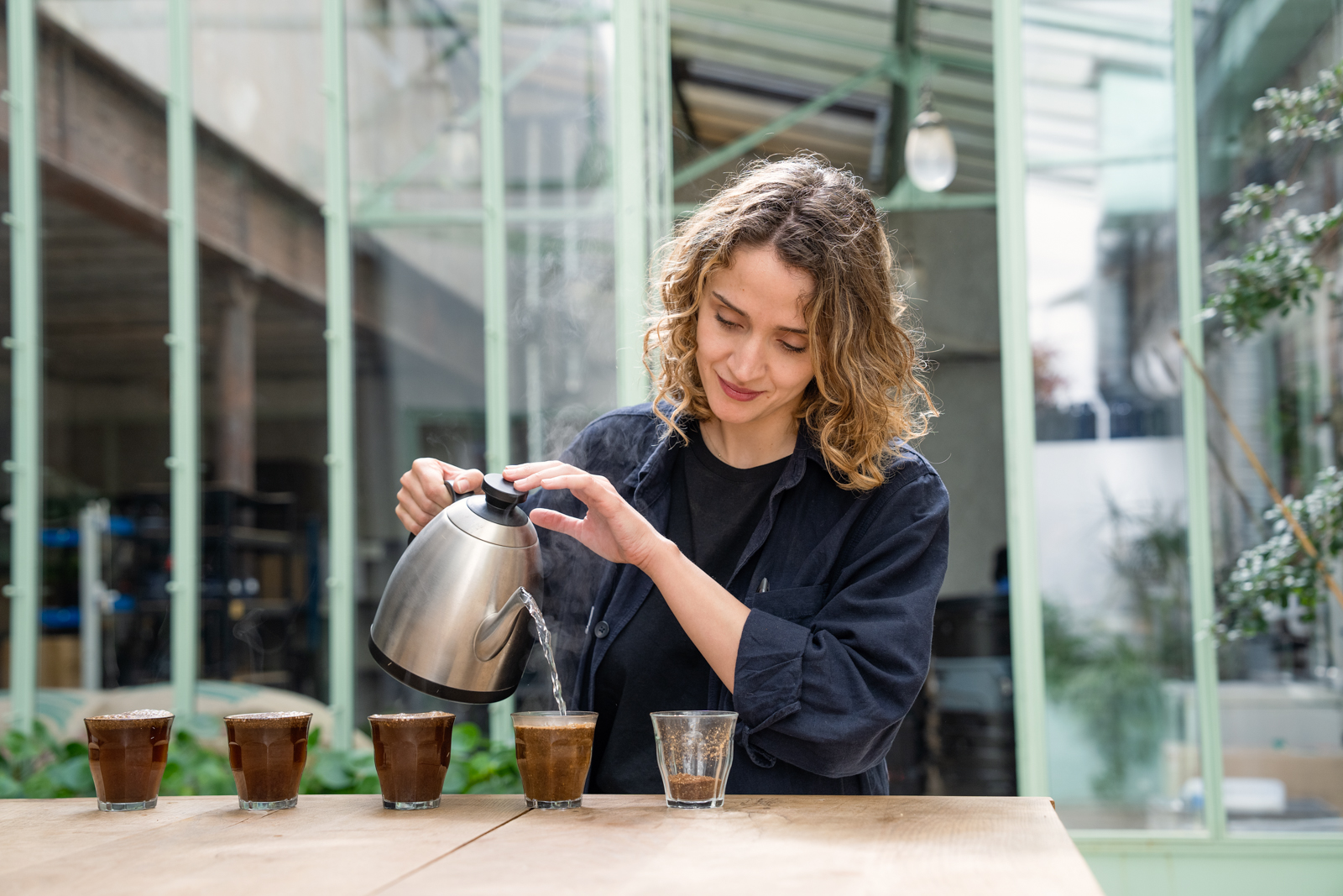 Woman pouring hot water into cups of coffee for tasting