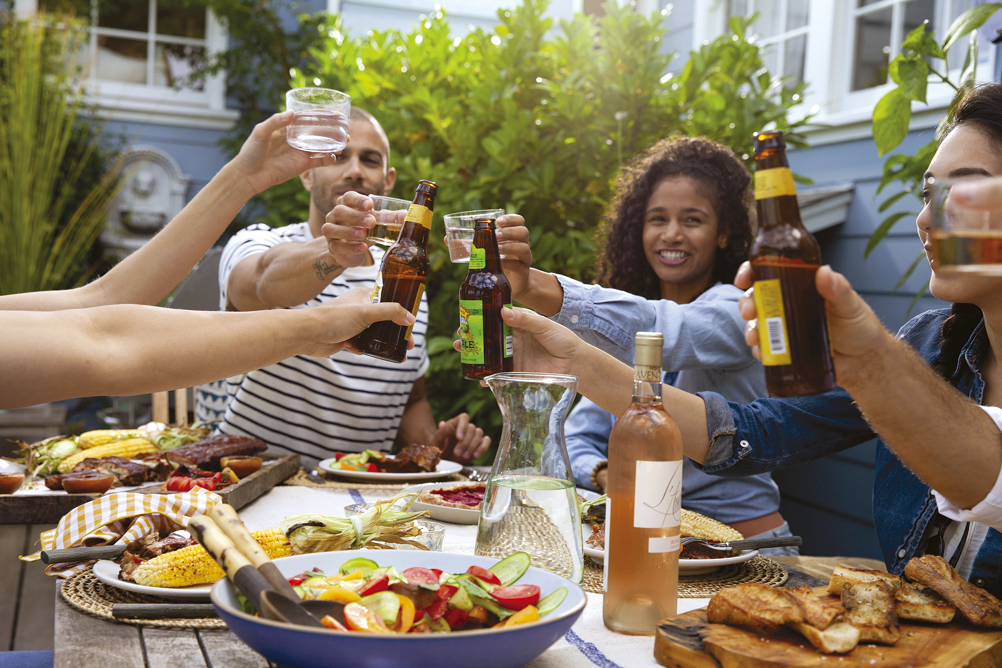 A group of friends hosting a backyard grilling party cheers to good times and good people