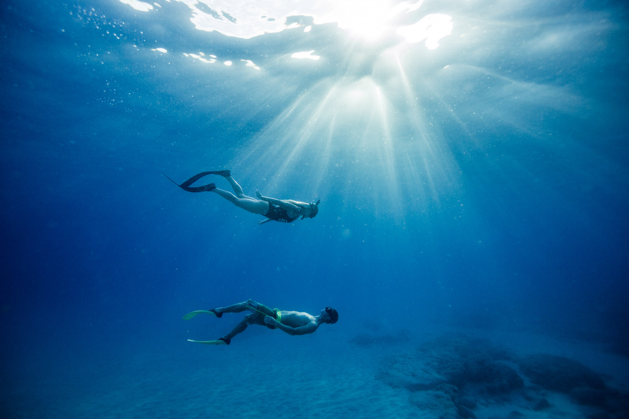A couple freedives together at Makua Beach on Oahu, Hawaii, as seen underwater.