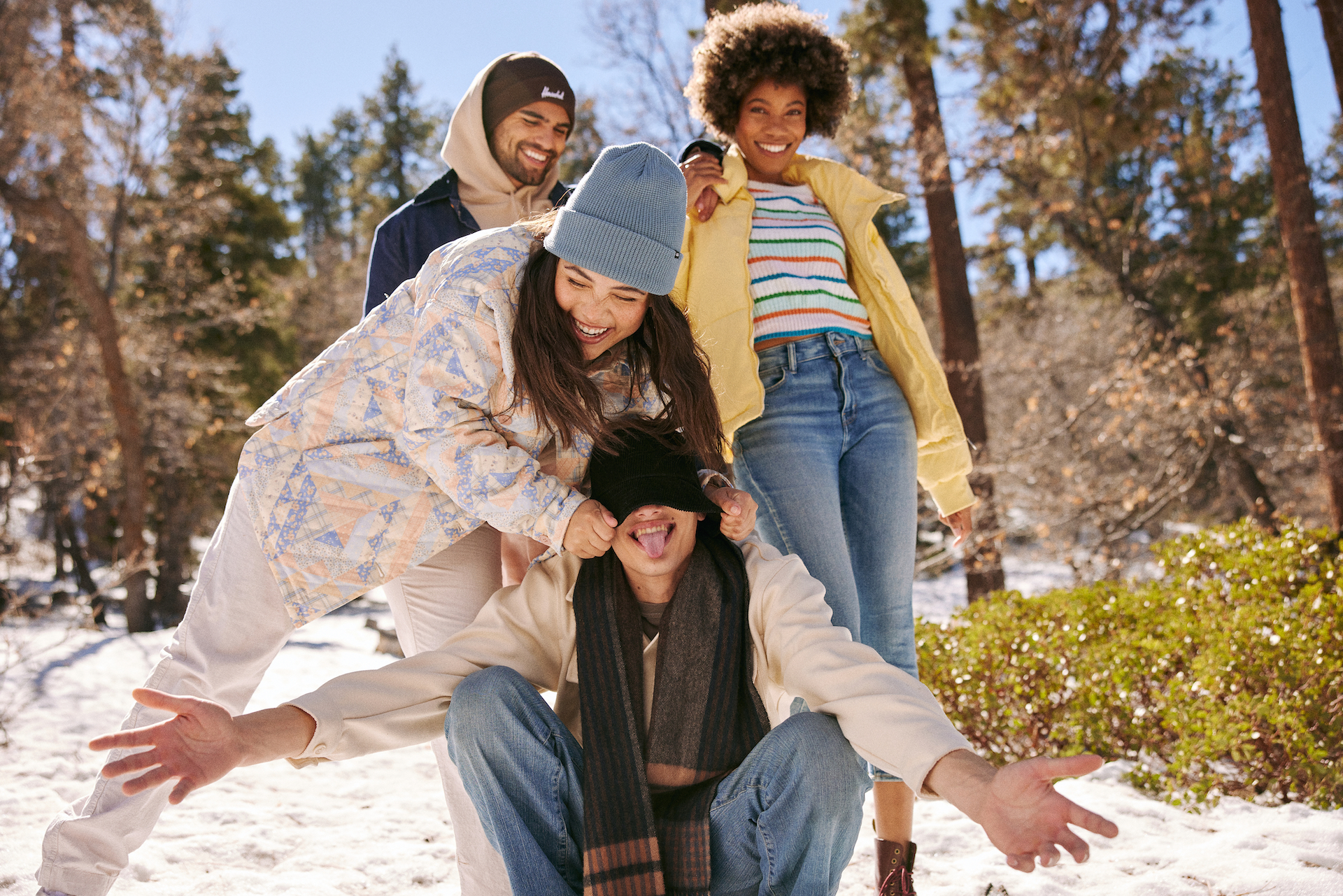 Outdoor lifestyle photograph of a group of friends hanging out in the snow, laughing.